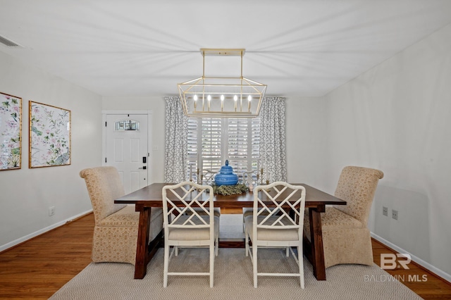 dining space with hardwood / wood-style floors and a chandelier