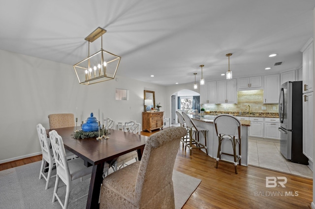 dining space with an inviting chandelier and light hardwood / wood-style flooring