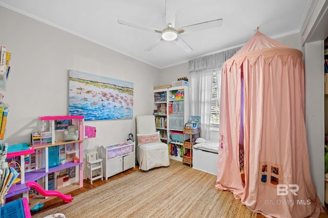 recreation room with ceiling fan, wood-type flooring, and ornamental molding