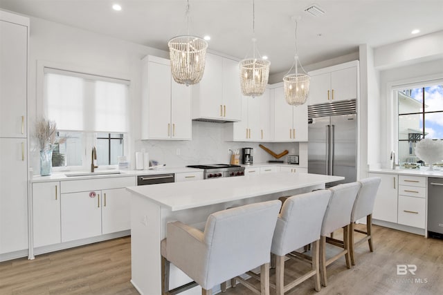 kitchen with a sink, white cabinetry, appliances with stainless steel finishes, and a kitchen breakfast bar