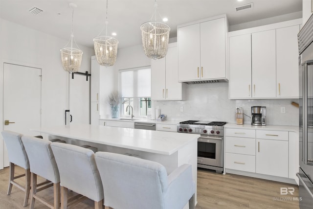 kitchen with visible vents, an inviting chandelier, a sink, light wood finished floors, and appliances with stainless steel finishes