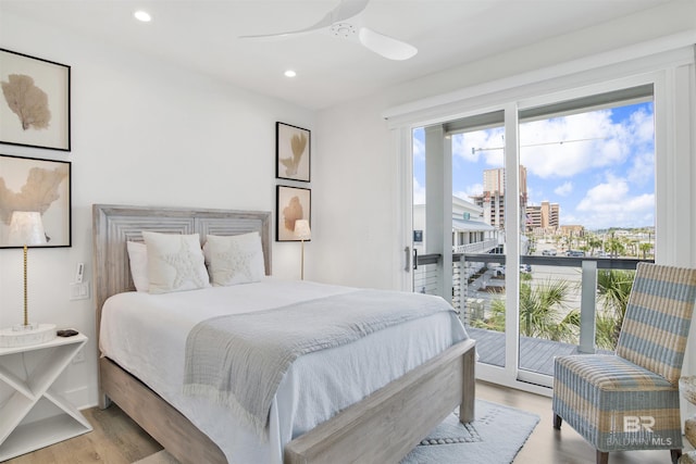 bedroom with multiple windows, a city view, recessed lighting, and wood finished floors