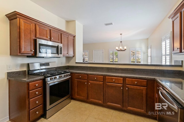 kitchen with kitchen peninsula, appliances with stainless steel finishes, a notable chandelier, hanging light fixtures, and light tile patterned flooring