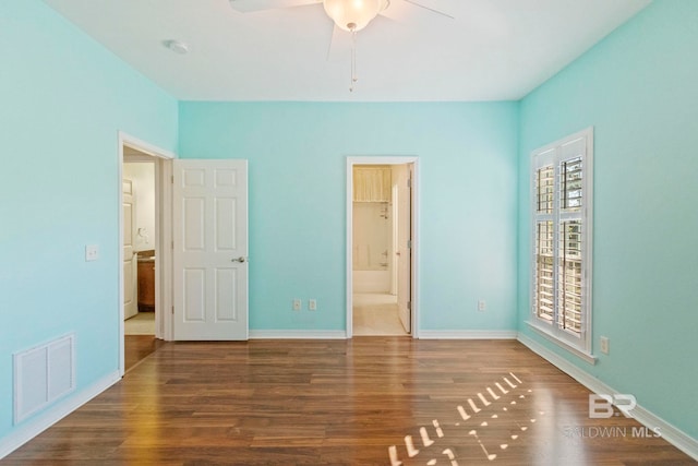 unfurnished bedroom featuring ensuite bath, ceiling fan, hardwood / wood-style floors, and a spacious closet