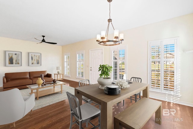 dining space featuring dark hardwood / wood-style floors and ceiling fan with notable chandelier