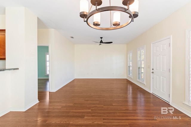 entryway with ceiling fan with notable chandelier and dark wood-type flooring