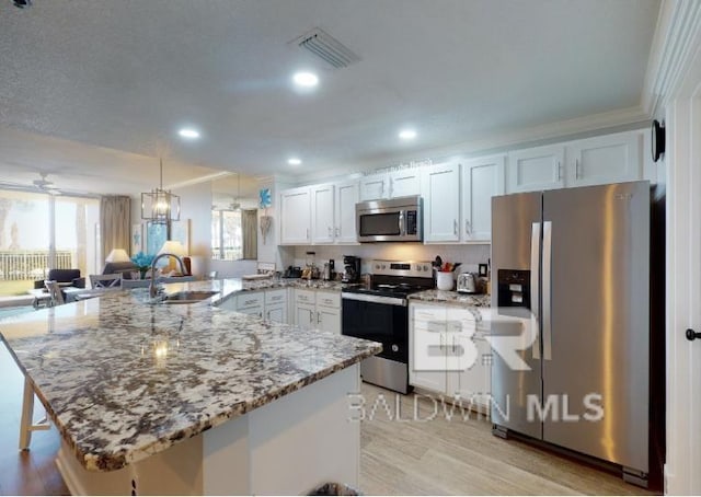 527C Beach Club Trl Unit C-0104, Gulf Shores, AL 36542 - kitchen featuring stainless steel appliances, a peninsula, light wood-style floors, healthy amount of natural light, and ornamental molding