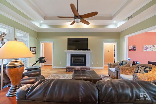 living room featuring visible vents, a raised ceiling, ornamental molding, and a fireplace