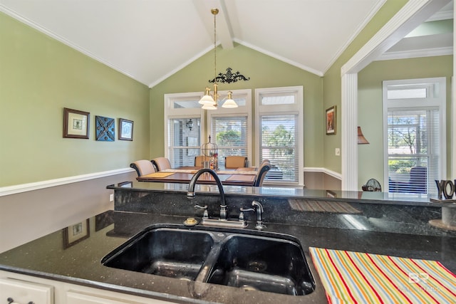 kitchen featuring lofted ceiling with beams, ornamental molding, dark stone countertops, and a sink