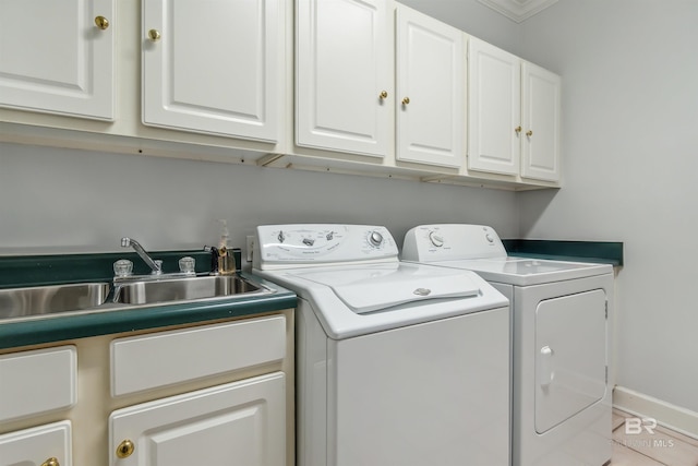 clothes washing area featuring cabinet space, independent washer and dryer, baseboards, and a sink