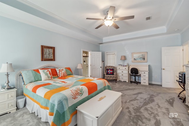 bedroom with visible vents, a tray ceiling, ornamental molding, light carpet, and a ceiling fan