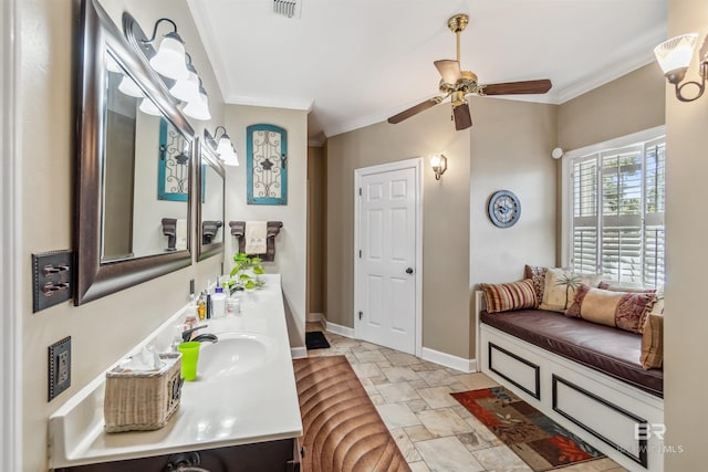 full bath featuring visible vents, stone tile flooring, crown molding, double vanity, and baseboards