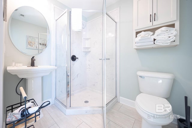 bathroom with tile patterned floors, toilet, and a shower with door