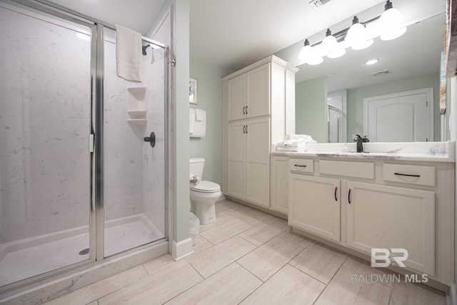 bathroom featuring vanity, a shower with shower door, and toilet