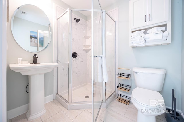 bathroom featuring tile patterned floors, toilet, and a shower with door