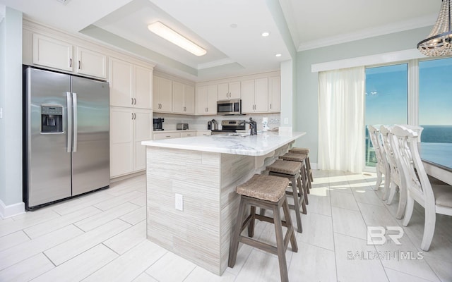 kitchen with white cabinetry, stainless steel appliances, tasteful backsplash, a kitchen bar, and decorative light fixtures