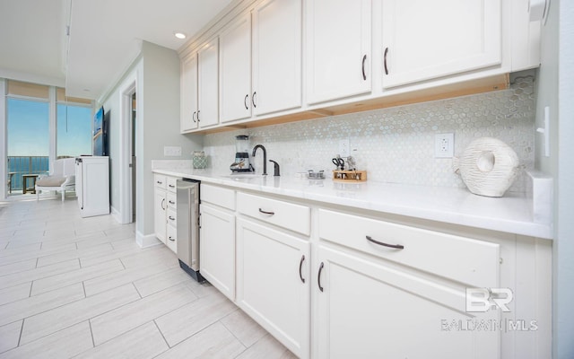 kitchen featuring white cabinets, a wall of windows, sink, and backsplash