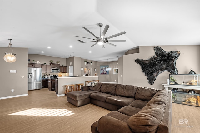 living room featuring light hardwood / wood-style floors, vaulted ceiling, and ceiling fan