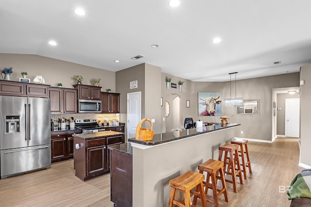 kitchen with hanging light fixtures, decorative backsplash, appliances with stainless steel finishes, a kitchen island, and dark brown cabinetry