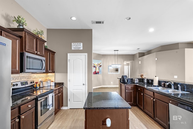 kitchen featuring sink, a center island, stainless steel appliances, dark brown cabinets, and light wood-type flooring