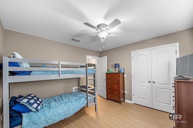 bedroom with ceiling fan, light hardwood / wood-style floors, and a closet