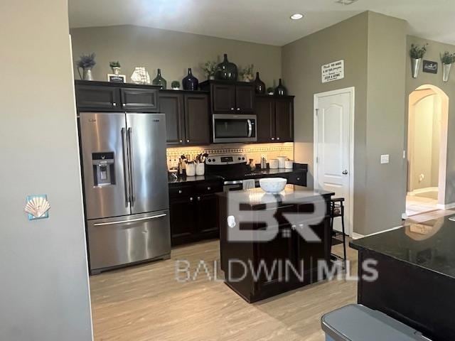 kitchen featuring backsplash, a kitchen island, stainless steel appliances, and light hardwood / wood-style flooring