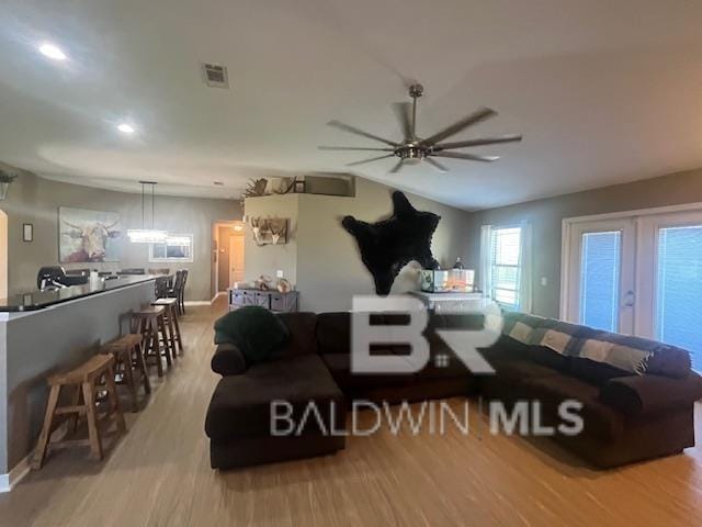 living room featuring ceiling fan, vaulted ceiling, and light hardwood / wood-style flooring