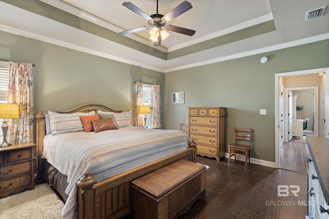 bedroom with visible vents, hardwood / wood-style flooring, a raised ceiling, baseboards, and ornamental molding