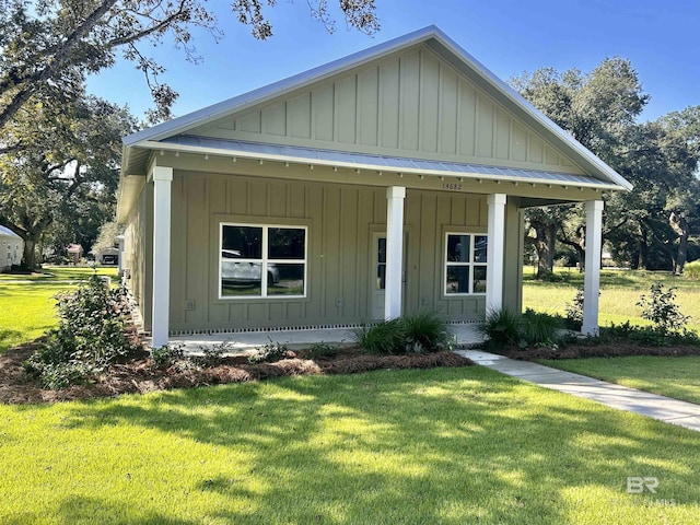 view of front of house with a standing seam roof, metal roof, a front lawn, and board and batten siding