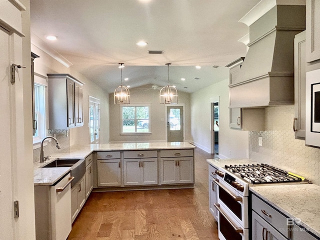 kitchen featuring white appliances, hanging light fixtures, a peninsula, gray cabinetry, and a sink