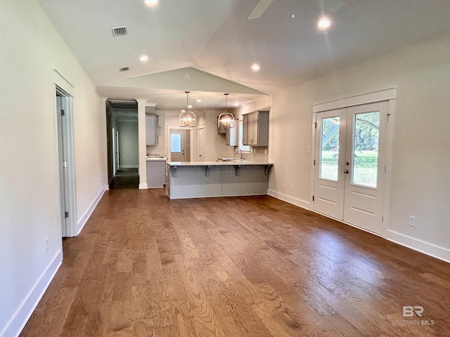 kitchen with dark wood-style flooring, pendant lighting, light countertops, a peninsula, and a kitchen bar