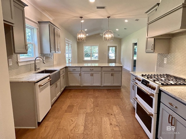 kitchen with a peninsula, white appliances, custom range hood, and a sink