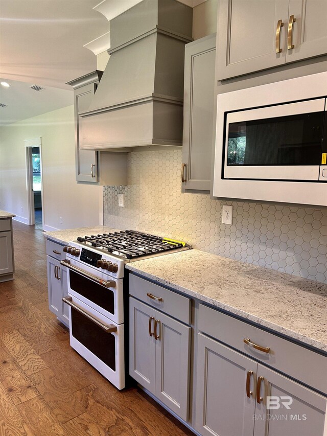 kitchen featuring range with two ovens, tasteful backsplash, gray cabinetry, built in microwave, and premium range hood