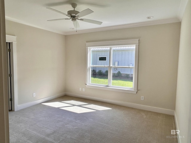 unfurnished room featuring a ceiling fan, baseboards, crown molding, and light colored carpet