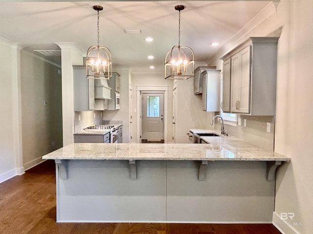 kitchen featuring a breakfast bar, decorative light fixtures, stainless steel appliances, a sink, and a peninsula