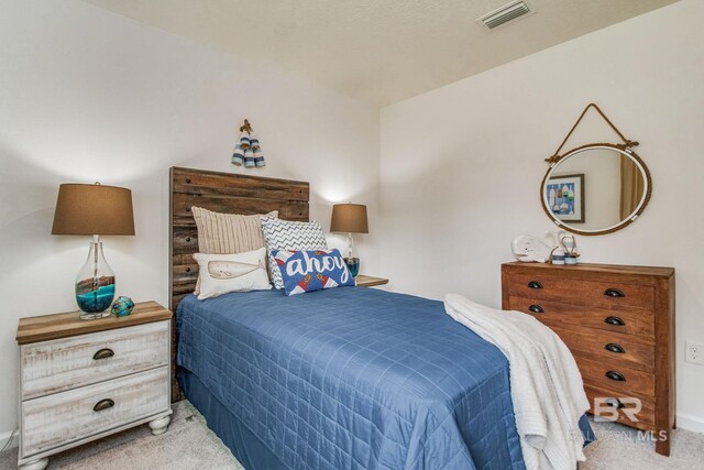 bedroom with baseboards, visible vents, and light carpet