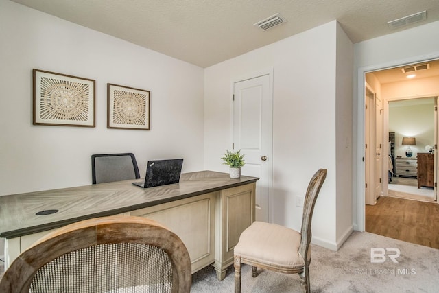 office area featuring baseboards, light carpet, and visible vents