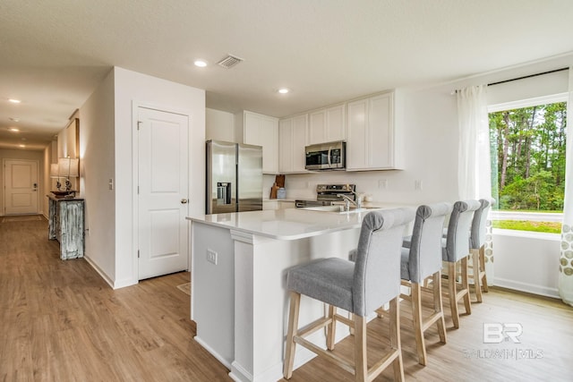 kitchen featuring a peninsula, baseboards, appliances with stainless steel finishes, and light wood-style floors