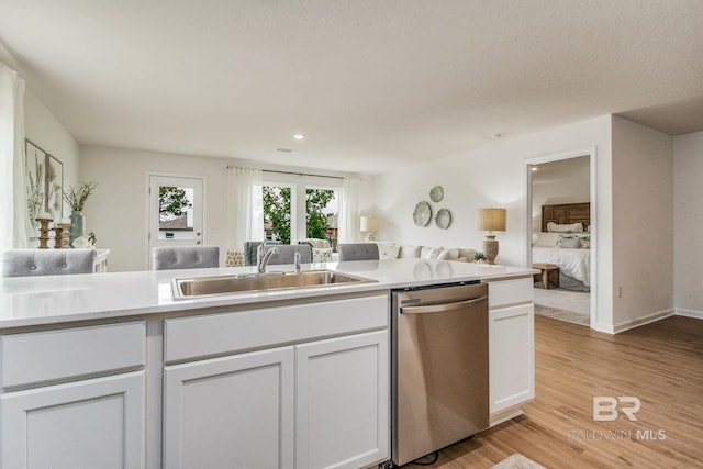 kitchen featuring light wood-style floors, open floor plan, light countertops, a sink, and dishwasher