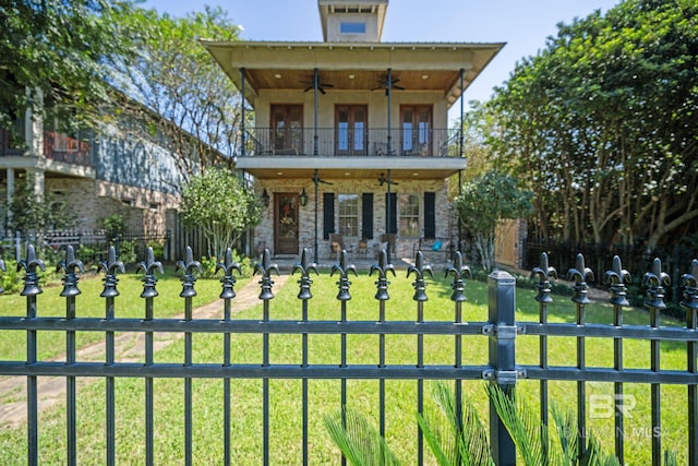 view of front facade with a front yard, a balcony, french doors, and ceiling fan