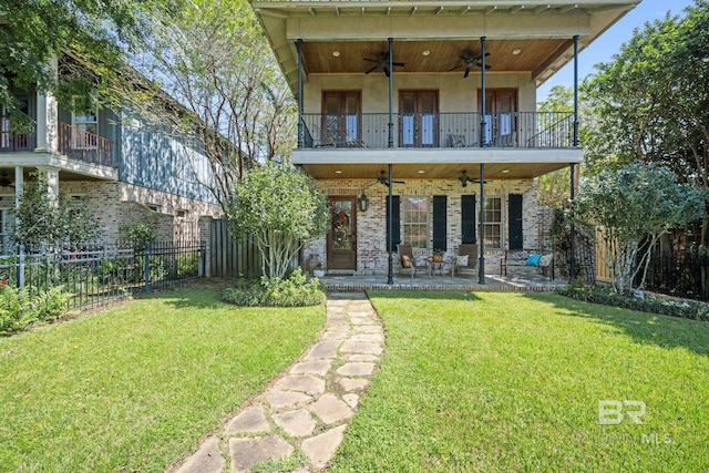 rear view of property featuring a balcony, a patio, ceiling fan, and a lawn