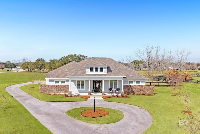 view of front of home featuring covered porch, curved driveway, a front yard, and fence