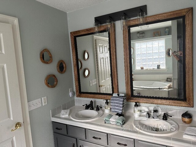 bathroom featuring a bathtub, vanity, and a textured ceiling