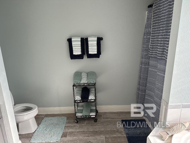 bathroom with curtained shower, toilet, and hardwood / wood-style flooring