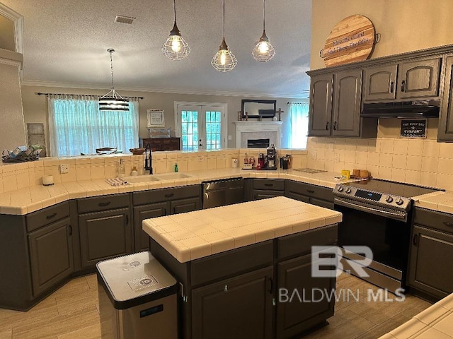 kitchen featuring electric range, sink, stainless steel dishwasher, a textured ceiling, and a kitchen island