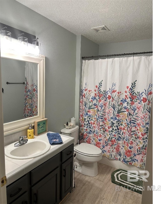 bathroom featuring hardwood / wood-style flooring, vanity, toilet, and a textured ceiling