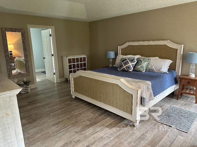 bedroom with a textured ceiling, lofted ceiling, and dark hardwood / wood-style floors