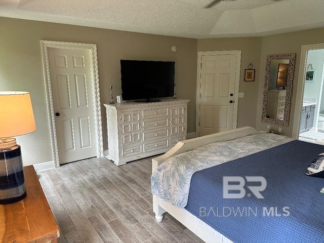 bedroom featuring ensuite bathroom, ceiling fan, a textured ceiling, and hardwood / wood-style flooring