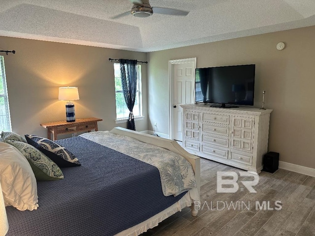 bedroom featuring ceiling fan, hardwood / wood-style floors, and a textured ceiling