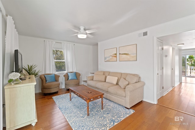 living room featuring visible vents, ceiling fan, baseboards, and wood finished floors